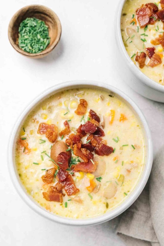 A bowl of corn chowder with bacon sprinkled on top.