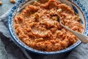 Blue and white bowl filled with Muhammara, or red pepper walnut spread with a spoon in it