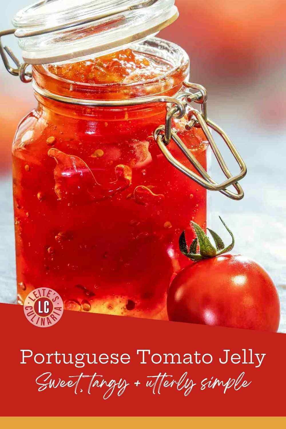 A glass hinge-top jar filled with vibrant red tomato jelly next to a fresh whole tomato on marble.