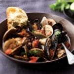Bowl of Portuguese fisherman's stew, which includes, clams, mussels, cod, tomatoes, and herbs--a slice of bread