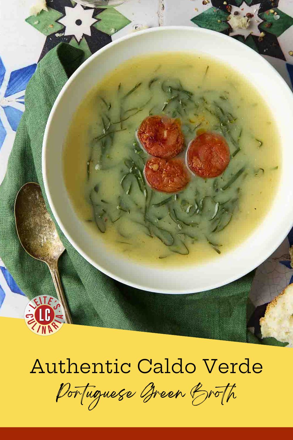 Close-up of caldo verde Portuguese green broth with collard greens and chouriço in a white bowl with a spoon.