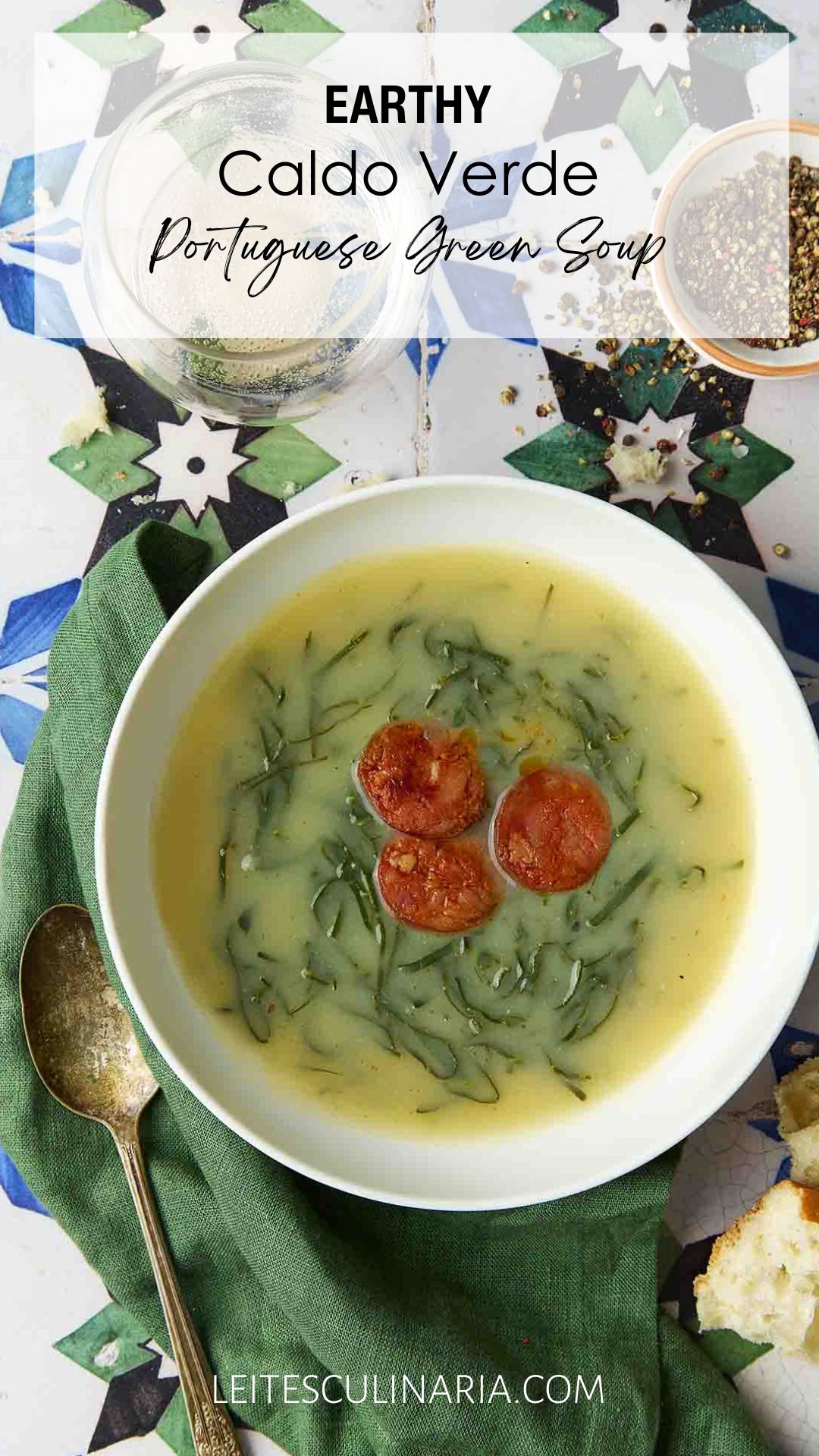 A white bowl of caldo verde, or Portuguese kale soup (green broth) with thinly sliced kale and three chourico coins floating in the center.