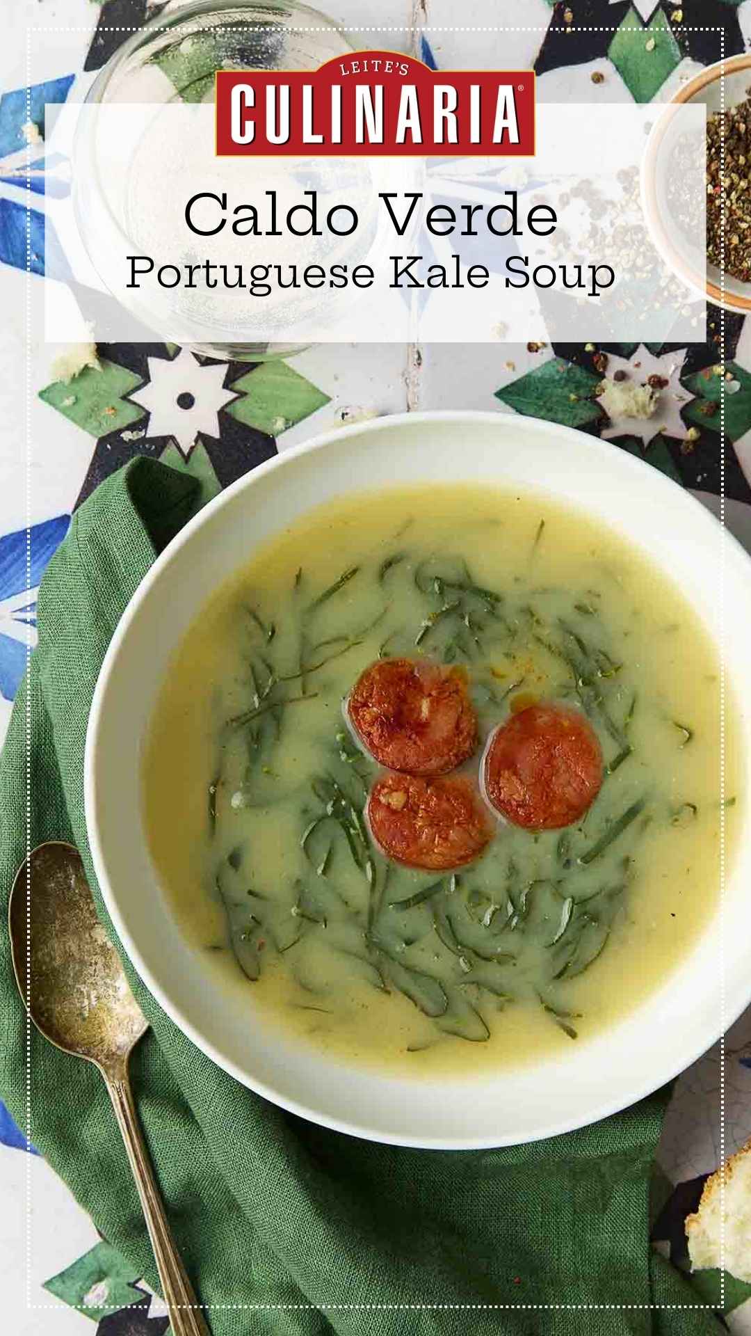 A white bowl of caldo verde, or Portuguese kale soup (green broth) with thinly sliced kale and three chourico coins floating in the center.