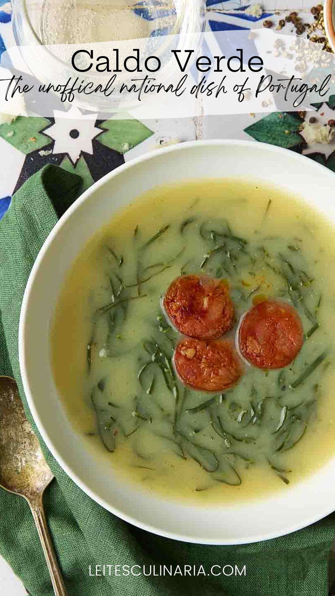 A white bowl of caldo verde, or Portuguese kale soup (green broth) with thinly sliced kale and three chourico coins floating in the center.