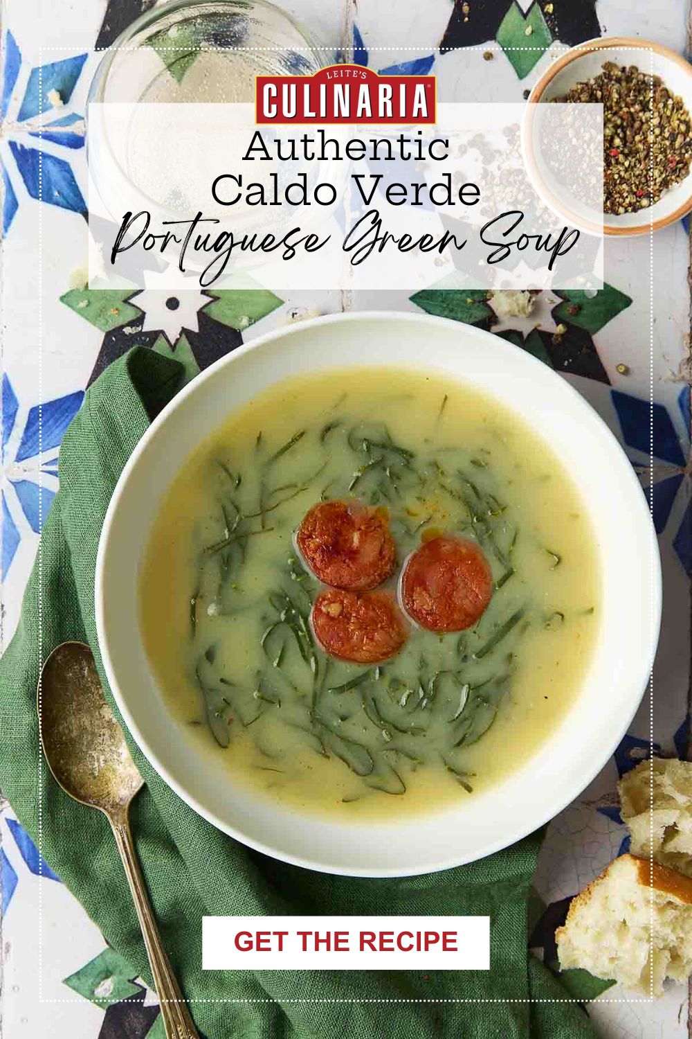 Bowl of traditional Portuguese caldo verde soup with chouriço slices, set on colorful tiles with rustic bread and a green napkin.