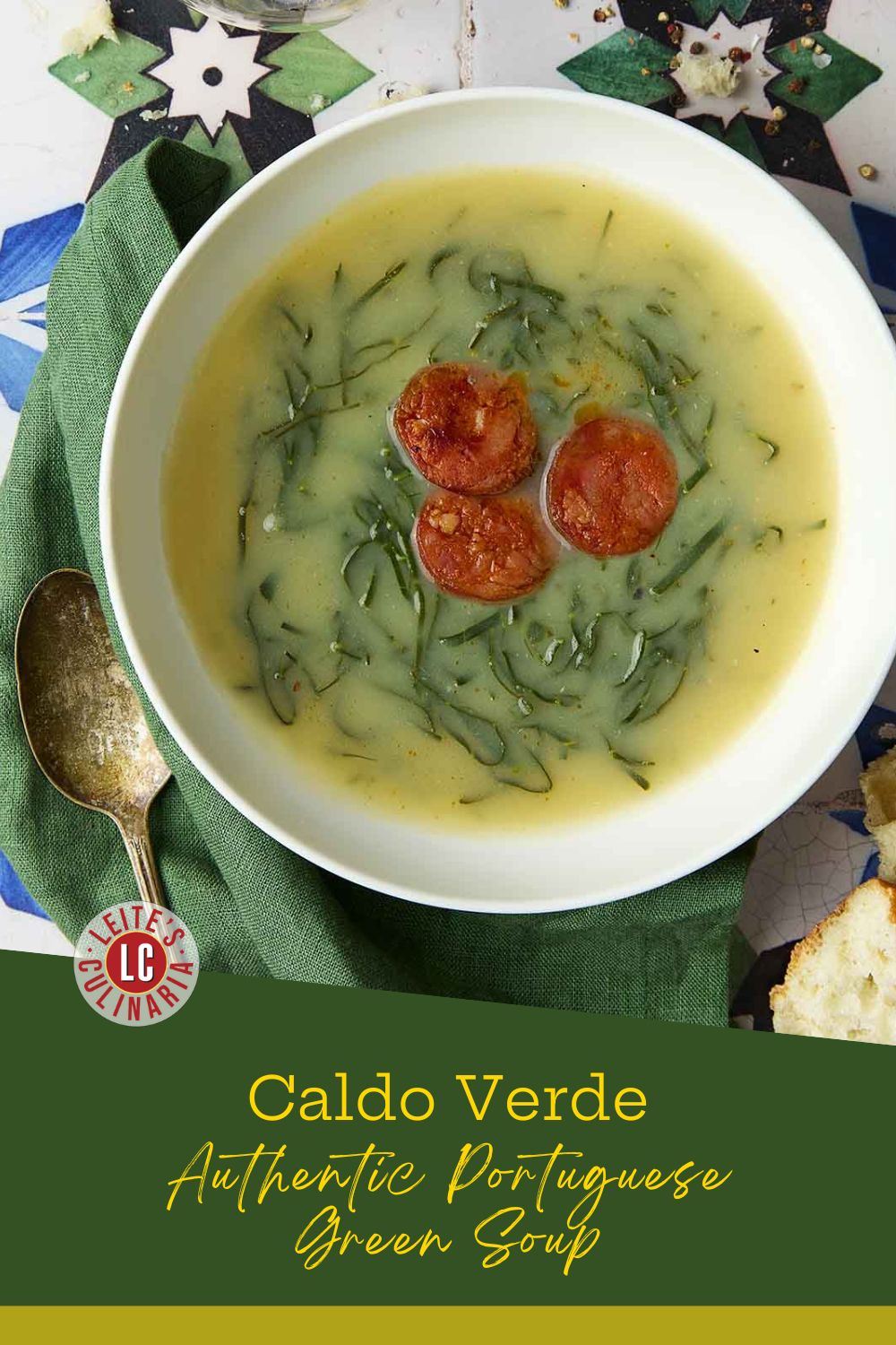 Caldo verde in a white bowl with sliced chouriço and finely shredded greens on a green napkin.
