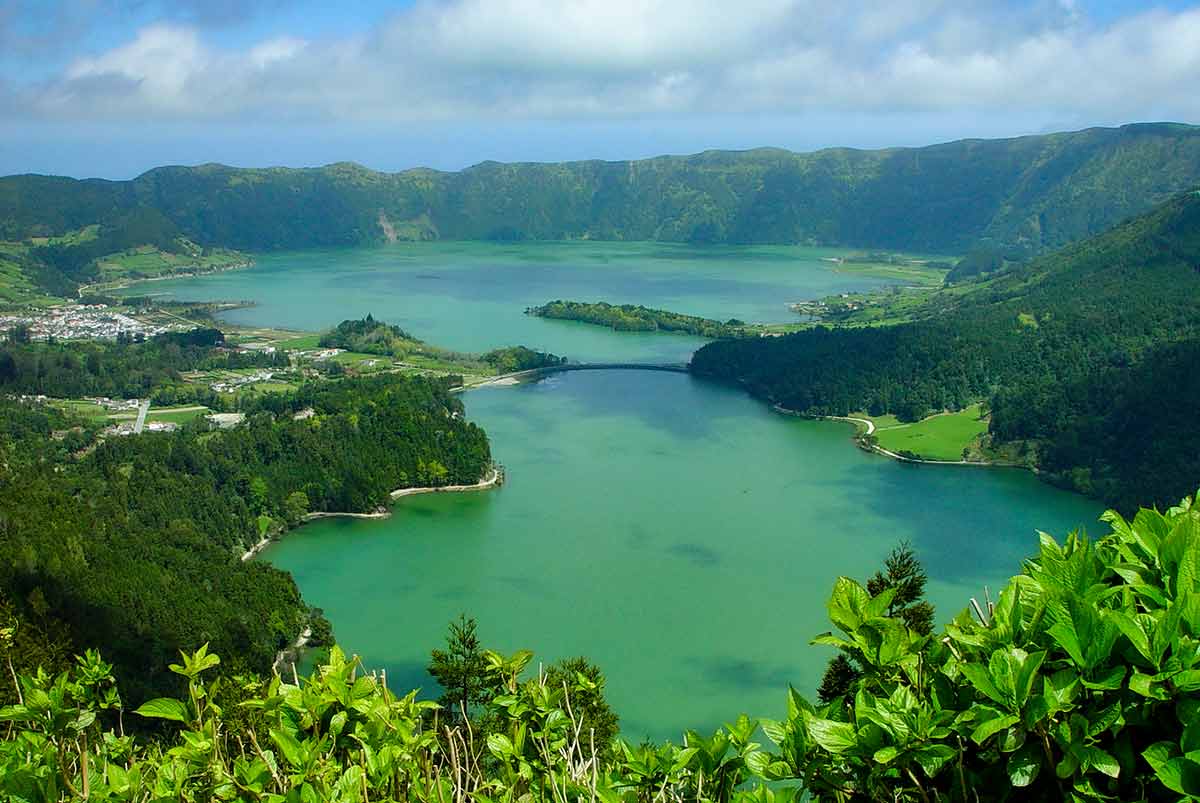 Gorgeous green and blue photo of Sete Cidades with clouds and trees.