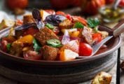 Wood bowl of panzanella from Ina Garten with bread chunks, tomatoes, peppers, cucumbers, basil, and parsley