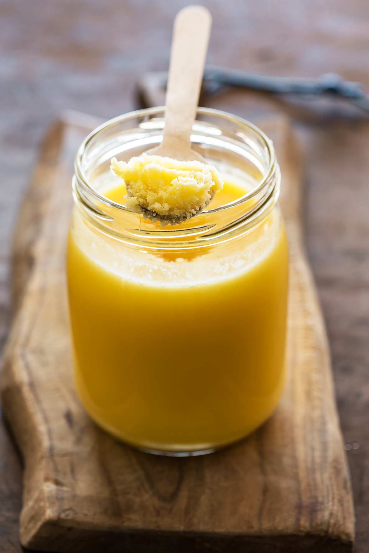 Mason jar filled with Indian ghee or clarified butter on a wooden plank