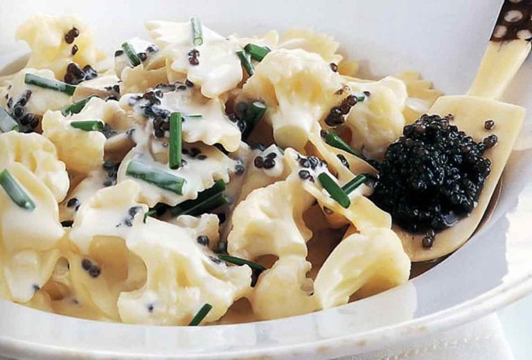 A bowl of bowtie pasta with caviar, in a cream sauce topped with chives