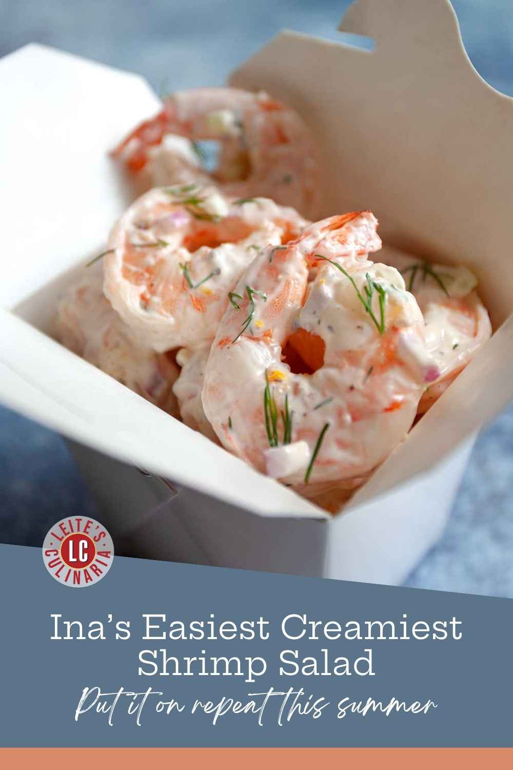 Plump, creamy shrimp salad tossed with fresh dill and red onion inside a white cardboard takeout container.