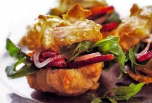 Gougeres, or cheese puffs, with arugula, bacon, and pickled onion on a metal plate