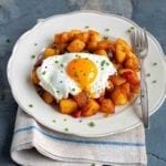 A white plate topped with chunky ranch-style home fries topped with a fried egg.