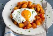 A white plate topped with chunky ranch-style home fries topped with a fried egg.