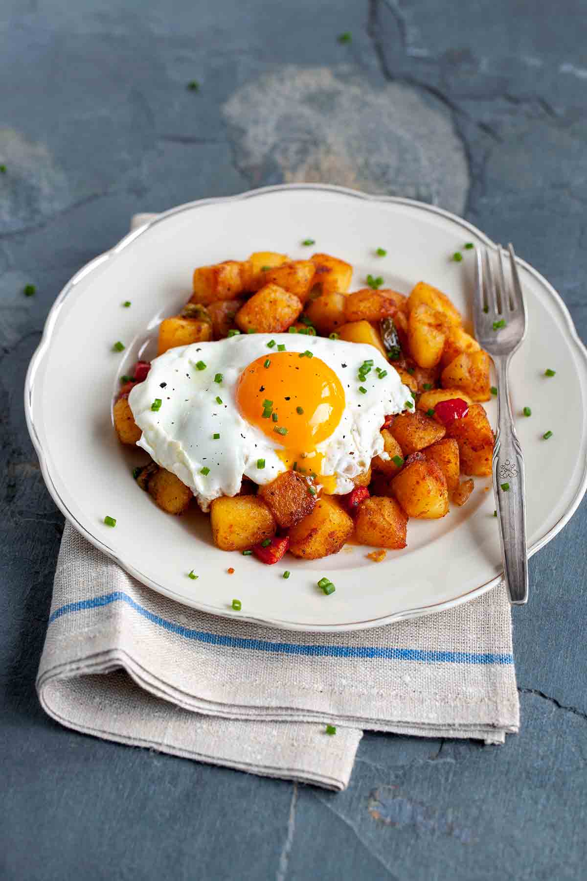 A white plate topped with chunky ranch-style home fries topped with a fried egg.