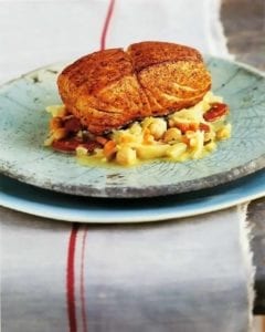 Pan-Roasted Halibut, Chickpeas and Chorizo on a blue earthenware plate on a table with a white runner with a red stripe.