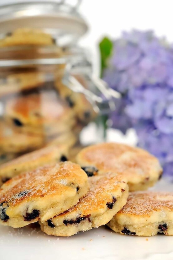 Welsh Cakes photographed on a white table with a purple hydrangea behind them.