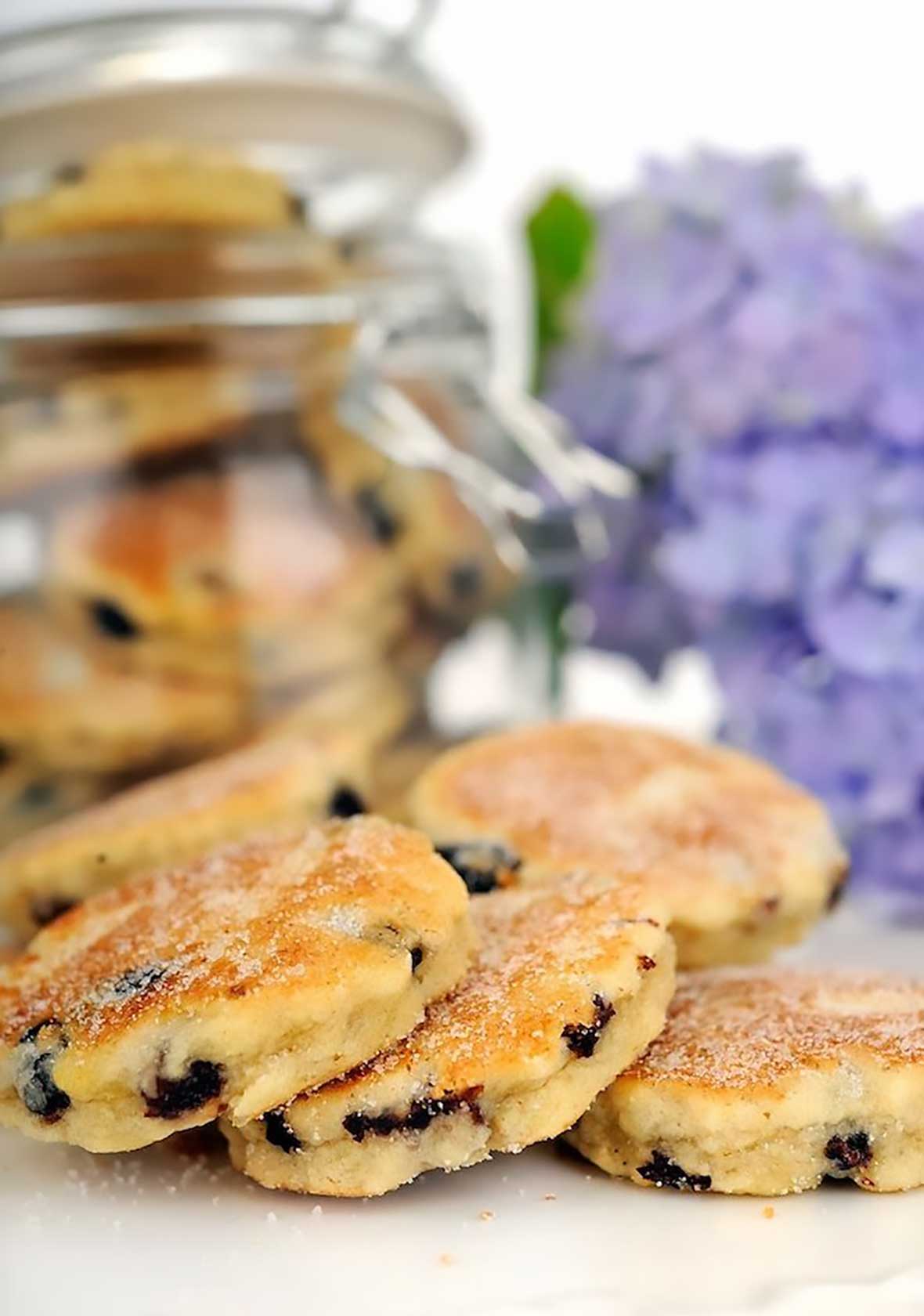 Welsh Cakes photographed on a white table with a purple hydrangea behind them.