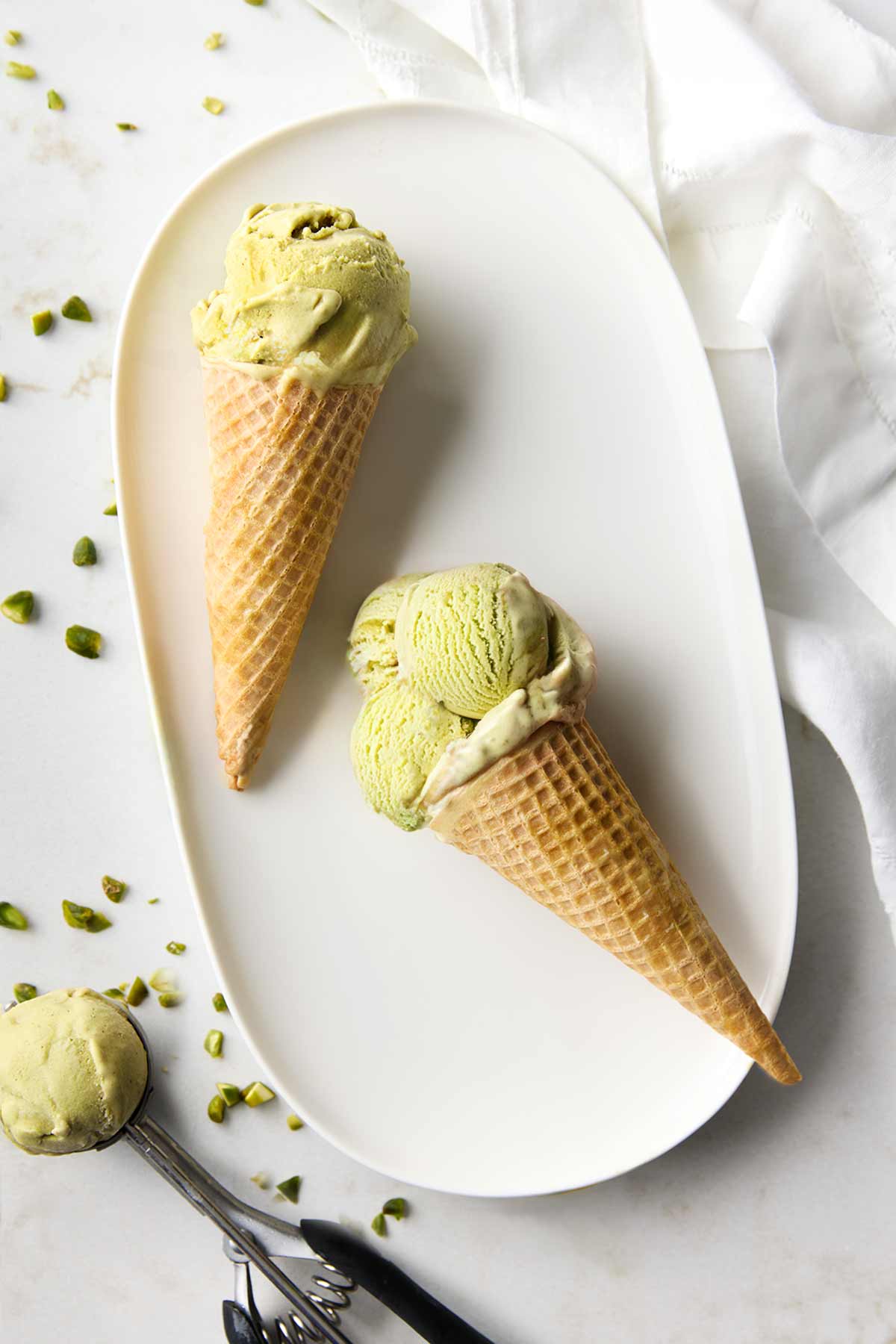 A platter with two ice cream cones filled with pistachio gelato.
