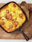 Portuguese Chourico Frittata in a cast iron skillet on a wooden cutting board.