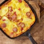Portuguese Chourico Frittata in a cast iron skillet on a wooden cutting board.