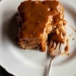 A square of Edna Lewis's apple cake with caramel glaze on a white plate with a fork.
