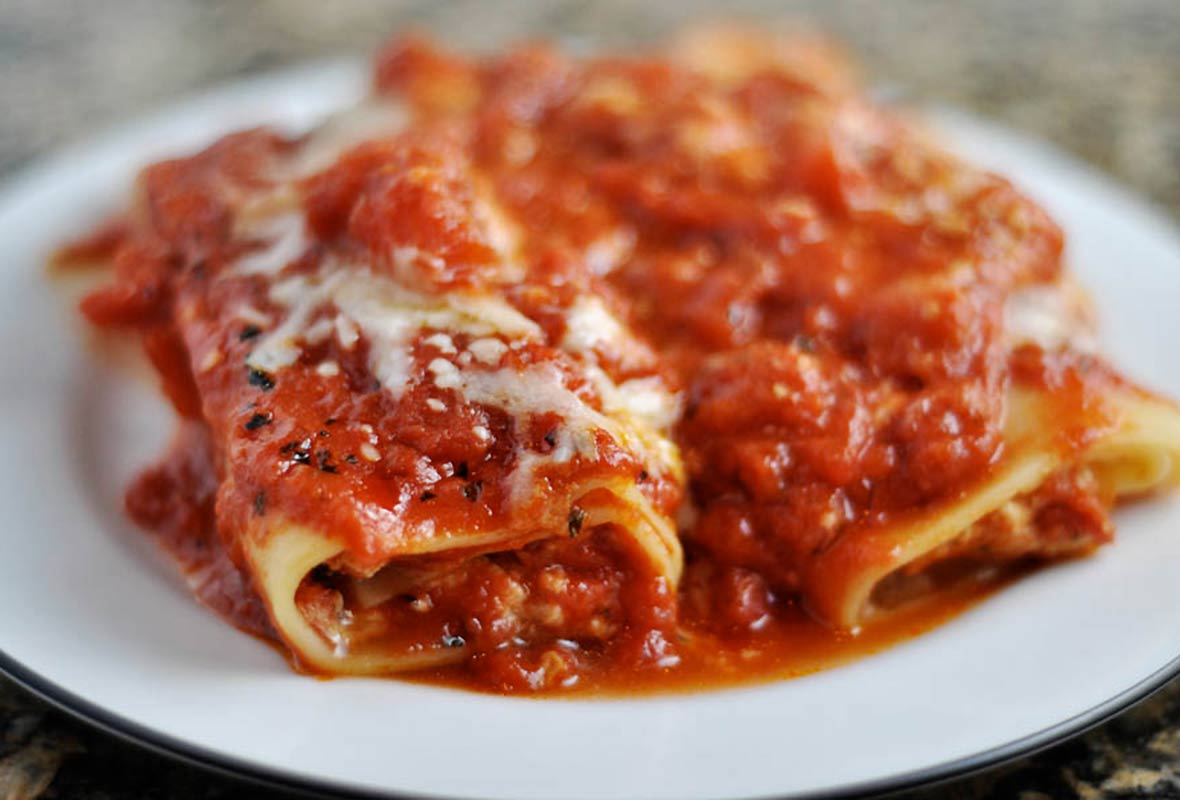 White plate with two rolled manicotti on it