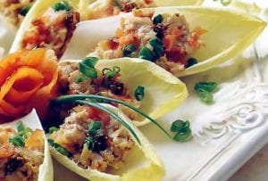 Endive leaves stuffed with cream cheese spread with smoked salmon with chopped chives on top.