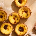 Close up of authentic pastel de nata Portuguese egg tarts on a plate sprinkled with powdered sugar.