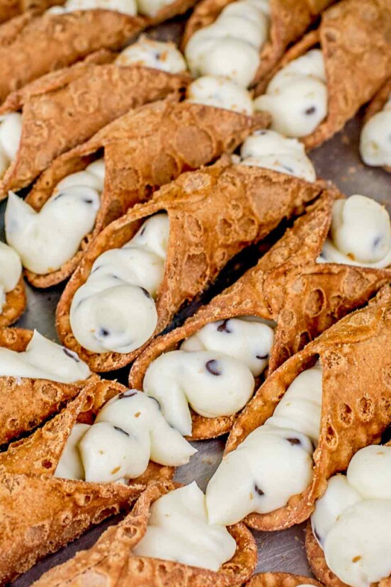 Sheet pan of 2 dozen cannoli filled with sweet ricotta filling and chocolate chips