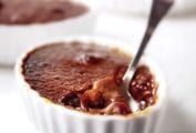 An individual cherry-chocolate creme brulee with a spoon resting in it.
