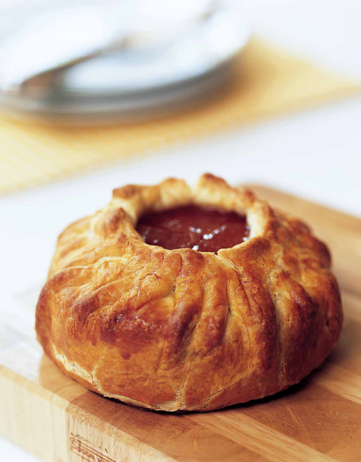 A wheel of brie cheese baked pastry, on top is a dollop of apricot preserves