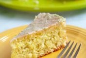 A slice of coconut lime macadamia cake on a yellow plate with a fork resting beside it