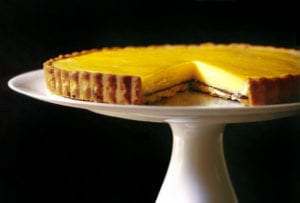 Meyer lemon tart on a white cake stand black background