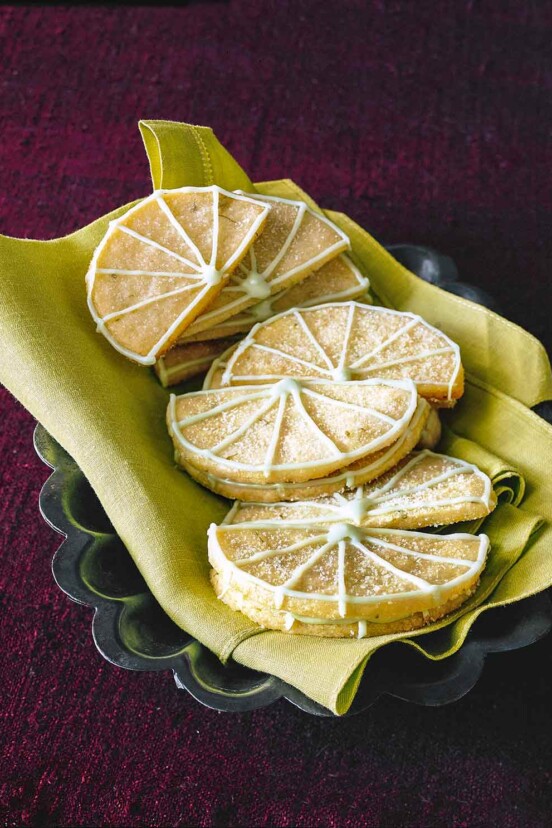 12 Key lime sugar cookies in the shape of lime wedges with lime icing.