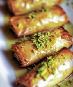 Four phyllo pastries stuffed with nuts, honey, and orange blossom water, and topped with pistachios and more honey.
