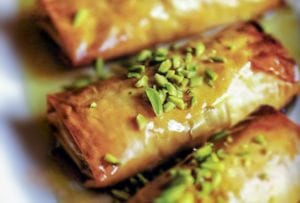 Four phyllo pastries stuffed with nuts, honey, and orange blossom water, and topped with pistachios and more honey