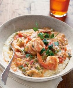 A white bowl filled with Tennessee shrimp and grits, topped with a sprig of parsley.