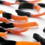 Strips of chocolate dipped candied orange peel on a white surface.