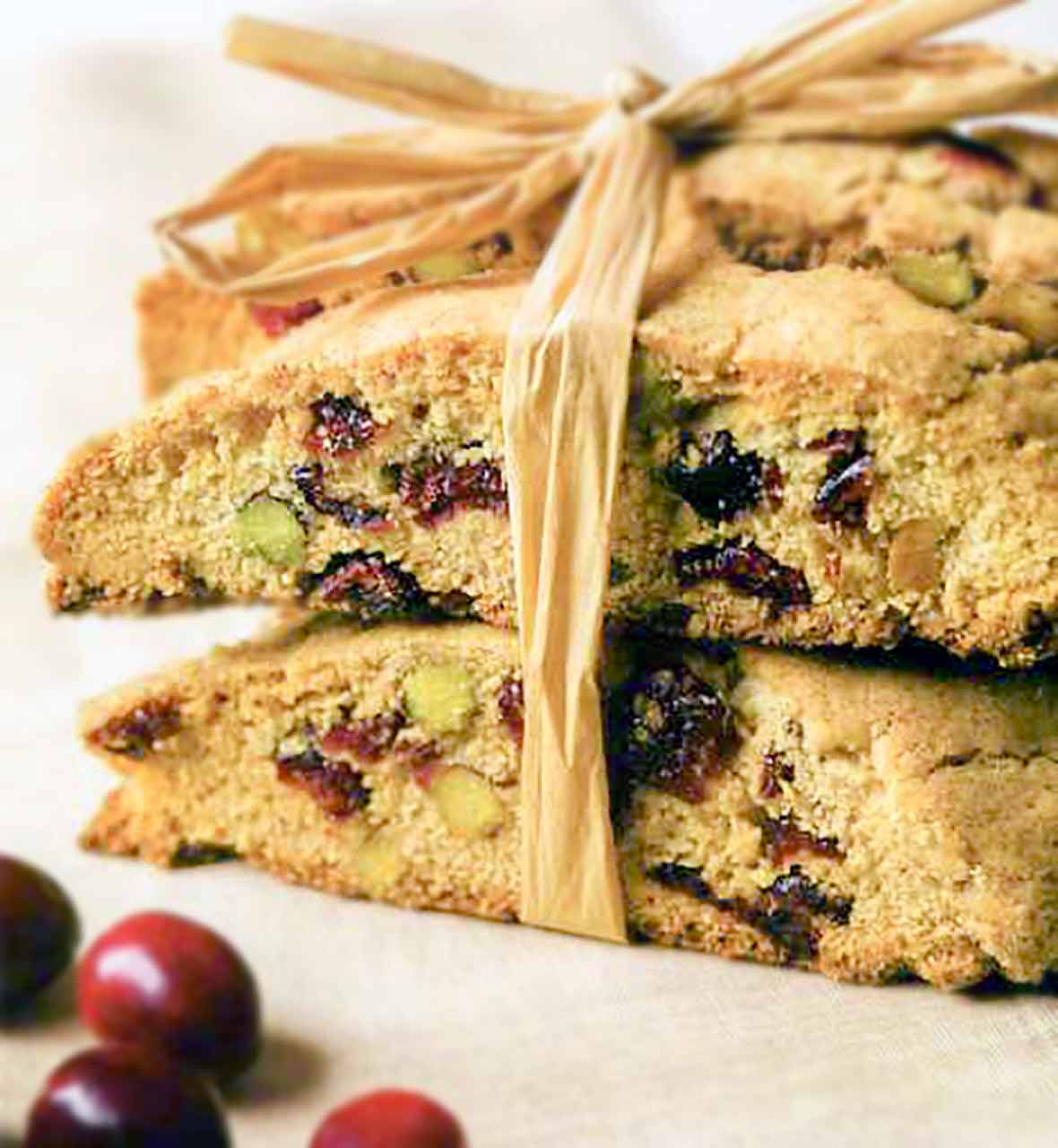 Several cranberry pistachio biscotti cookies tied together with raffia
