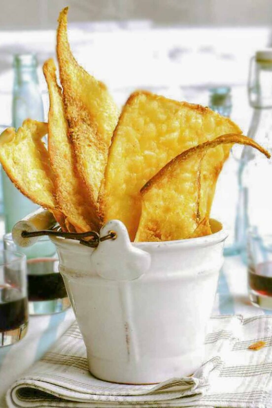 White bucket filled with rustic golden brown Parmesan flatbreads on a plaid napkin