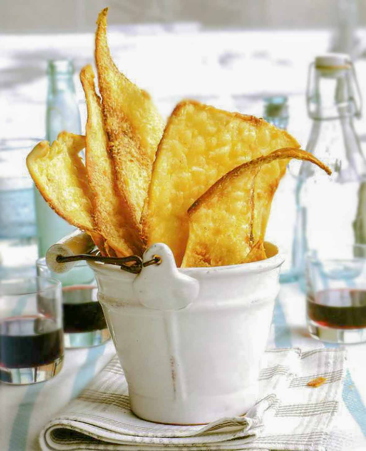 White bucket filled with rustic golden brown Parmesan flatbreads on a plaid napkin