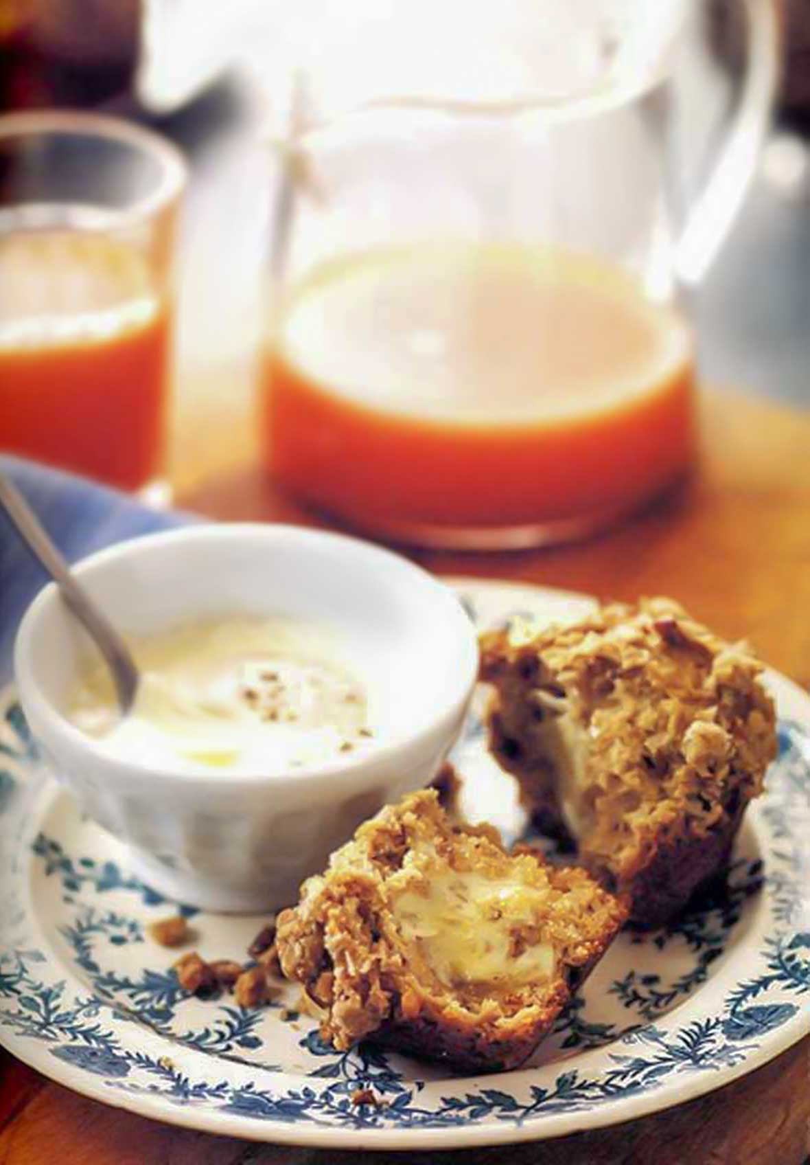 A cut streusel-topped date muffin slathered with butter on a decorative plate