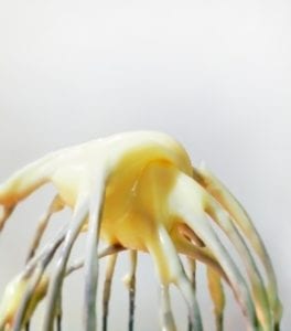 A whisk with homemade mayonnaise on it