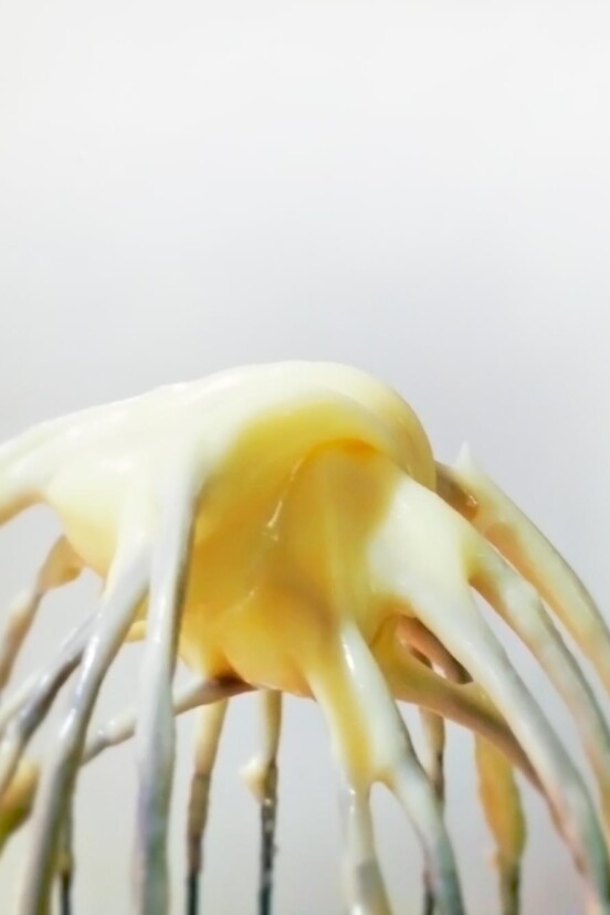 A whisk with homemade mayonnaise on it