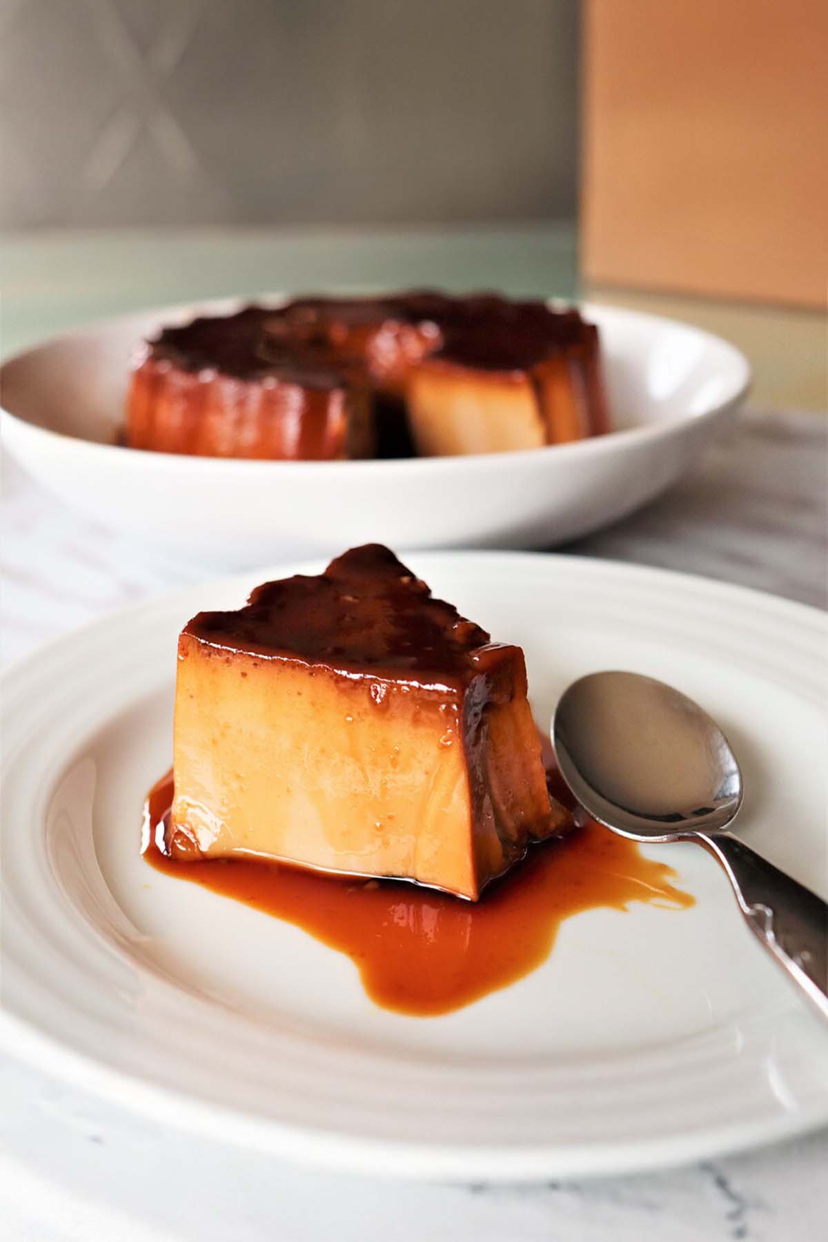 A piece of Portuguese tea flan on a white plate, drizzled with caramel sauce.