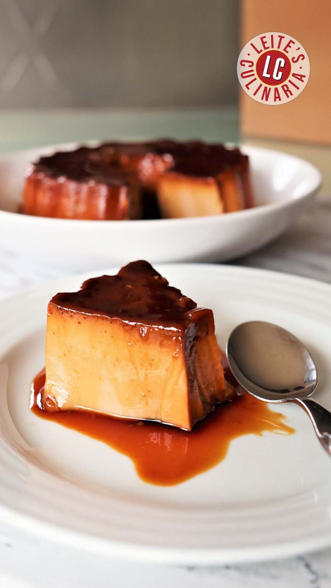 A piece of Portuguese tea flan on a white plate, drizzled with caramel sauce.