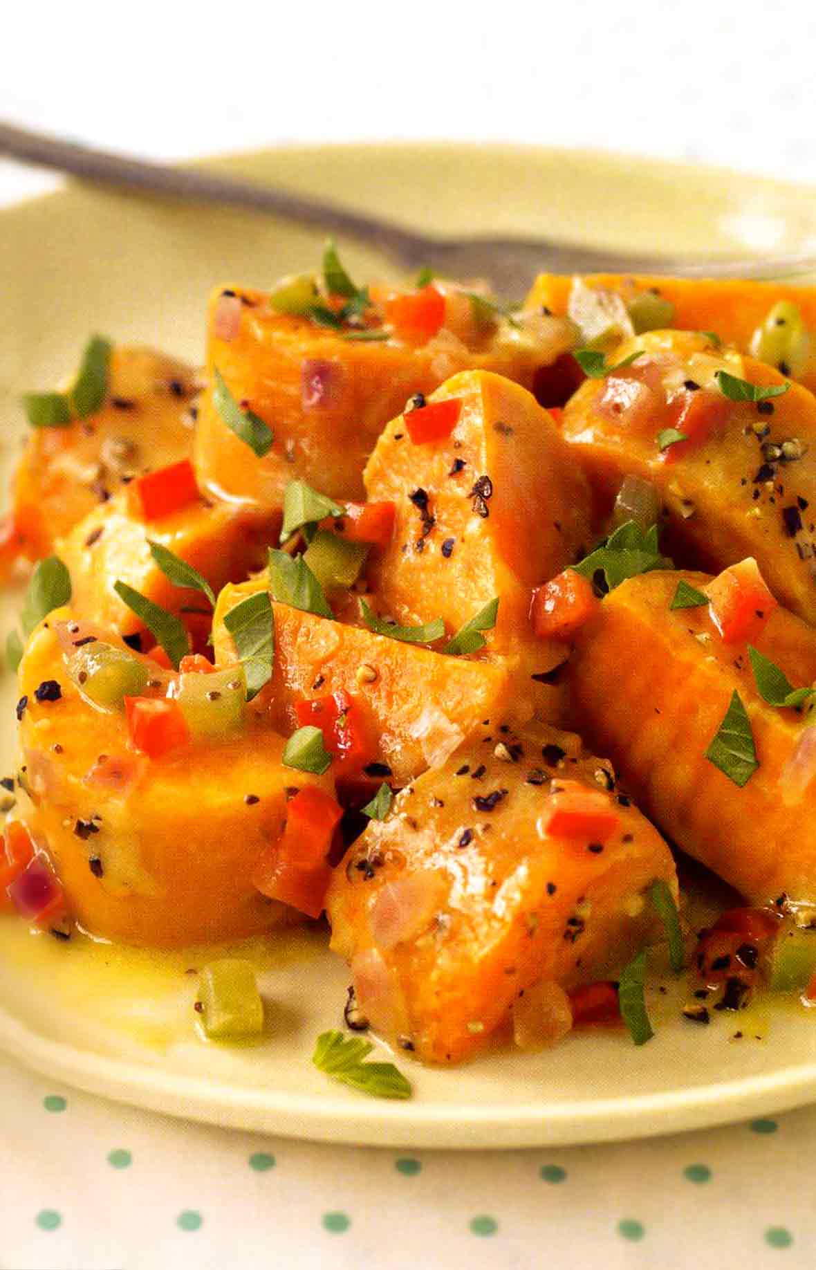 A plate of sweet potato salad sprinkled with cracked pepper, chopped parsley, and pickled pepper relish