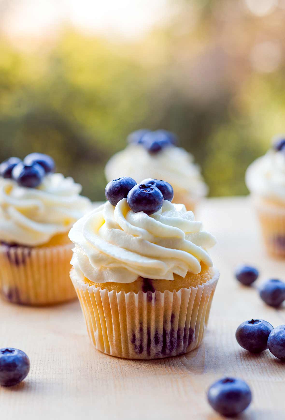 Several blueberry cupcakes topped with whipped cream and fresh blueberries.