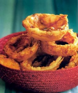 A red woven basket with a pile of buttermilk onion rings